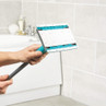 Extendable bathroom cleaning mop with white and teal head shown in use on tiled wall