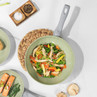 Green non-stick frying pan with cooked chicken stir fry and vegetables.