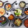 Grey non-stick cookware set displayed with assorted food to show cooking versatility
