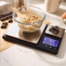 Digital kitchen scale with bowl of brown sugar and chocolate pieces, shown on worktop