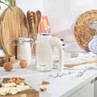 Cream hand mixer with beaters on kitchen counter, shown with baking ingredients