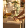Pale green stand mixer on kitchen counter, person kneading bread dough in warm sunlight