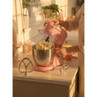 Pink stand mixer with bowl on kitchen counter, beating cake mixture, shown in natural light