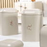 Set of cream kitchen storage canisters with rose gold 'C' and 'S', for tea, coffee, and sugar.