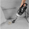 Handheld vacuum cleaning dust from grey fabric sofa