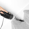 Handheld black and silver vacuum cleaner in use on carpeted stairs