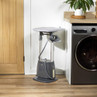 Grey garment steamer with ironing board in laundry room beside washing machine