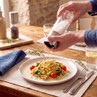 Silver salt mill seasoning pasta at the table