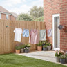 Retractable clothes line with washing hanging in garden, shown in use against brick wall.