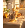 Yellow stand mixer with metal bowl on kitchen counter, includes whisk and dough attachments.