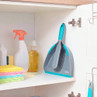 Grey dustpan and brush set with turquoise trim, stored in a cupboard with cleaning supplies.