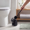 Black toilet brush and holder beside toilet