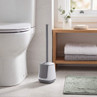 White and grey toilet brush holder beside toilet