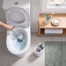 Open white toilet being cleaned with a toilet brush