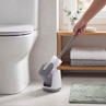 White toilet brush and holder beside toilet