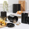 Set of black ribbed kitchen canisters for coffee, sugar, and bread displayed on counter