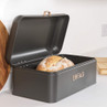 Black metal bread bin with hinged lid, labelled 'BREAD', containing a rustic loaf.