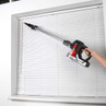 Cordless red and black handheld vacuum cleaner being used to clean window blinds