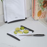 White plastic chopping board with black edge, lime cut in pieces and knife on kitchen counter
