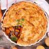 Steak and vegetable pie with golden pastry, one slice removed