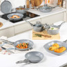Grey non-stick cookware set on kitchen counter, includes frying pans, saucepans and lids