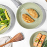 Green ceramic frying pan with cooked chicken breasts, shown from above