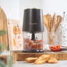 Black mini chopper with clear bowl, filled with chopped salsa ingredients