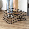 Black folding indoor clothes airer being unfolded beside a washing machine