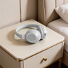 Grey wireless over-ear headphones on a bedside table