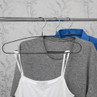 Three clothes hangers with a white vest, grey t-shirt, and blue shirt on a rail