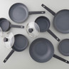 Set of non-stick black frying pans and saucepans with lids, shown from above.