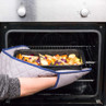 Hand placing tray of mixed root vegetables into an oven, shown using oven glove