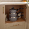 Set of three grey non-stick saucepans with lids, stacked in kitchen cupboard