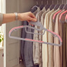 Grey non-slip clothes hangers with pink grips, shown in use in a wardrobe
