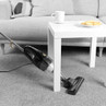 Corded stick vacuum cleaner cleaning under low table in lounge, showing slim design.