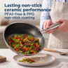 Silver ceramic non-stick frying pan pouring stir-fry, PFAS-free coating promotion