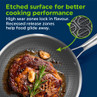 Etched non-stick frying pan with cooked steak, garlic and rosemary, surface detail shown.