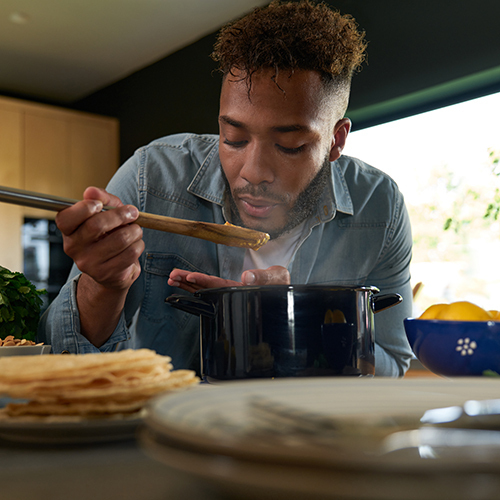 Man tasting food on a wooden spoon