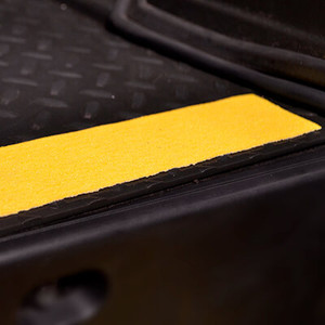 Yellow anti-slip floor tape applied to a textured surface, enhancing safety and visibility in industrial environments.