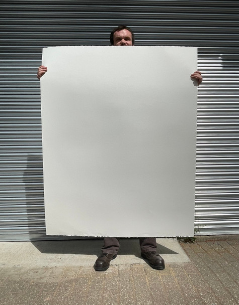 Tall artist holding a sheet of giant 400gsm watercolour drawing paper to demonstrate scale