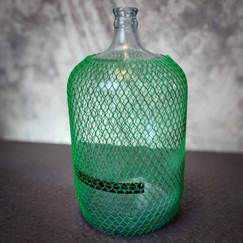A glass carboy jug, covered in a green Poly-Net HDPE Protective Mesh Netting Tube from Obtainium Science and Surplus, providing protection.