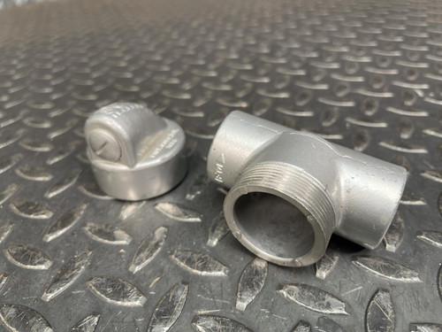 Killark EYS-2 1 inch conduit fitting showing the main body and separate sealing plug on a metal surface.