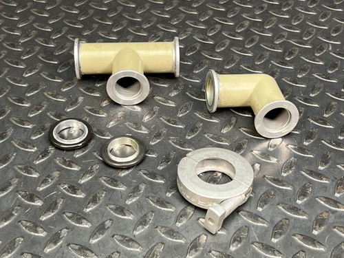 KF25 3-way tee, 90-degree elbow, clamp, and two centering rings on a diamond plate surface.