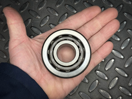 Timken 41106 taper roller bearing assembly held in a hand for scale against a diamond plate background.