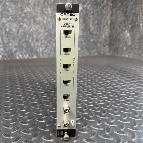 A close-up view of the front panel of an Ortec Model 427 Delay Amplifier. The amplifier has four input and output ports, labeled with different time delays: 0.25 μsec, 0.5 μsec, 1 μsec, and 2 μsec. The metal panel is mounted on a textured steel surface.