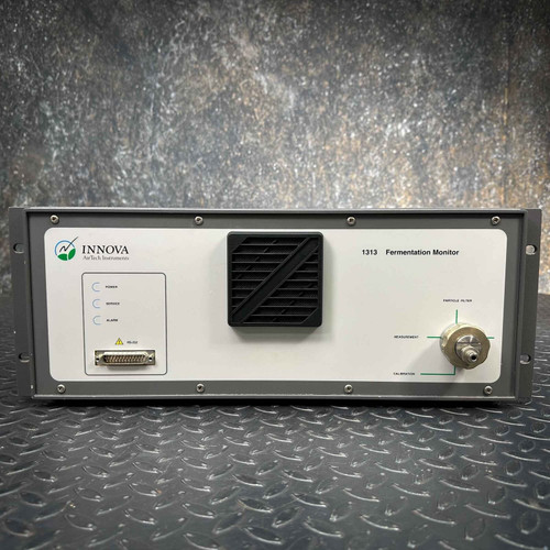 Front view of a LumaSense Innova 1313 Fermentation Monitor Analyzer, offered for parts. The grey rackmount style unit features a white front panel displaying the Innova AirTech Instruments logo and "1313 Fermentation Monitor" text. Visible details include power, sensor, and alarm status indicator labels, a DB9 serial port connector, a prominent black square fan grille, and a metal quickconnect style fitting on the right side with labels for Particle Filter, Measurement, and Calibration inputs, highlighted by green lines. This scientific lab instrument is shown against a dark, textured background.