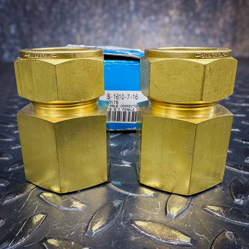 Two Swagelok B-1610-7-16 1 inch brass female connectors on a metal surface, showing the packaging label.
