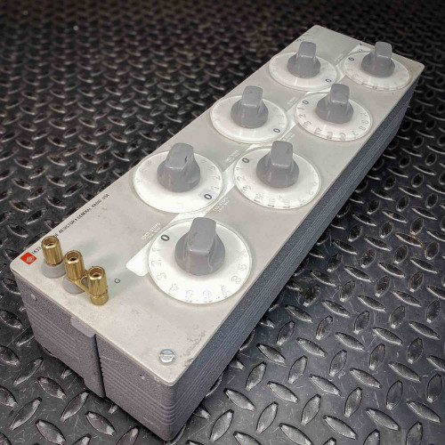 Angled view of a General Radio GenRad 1433-F Decade Resistor Box from Obtainium Science and Surplus, showing six gray dials on a rectangular metal enclosure with brass connectors on one end.