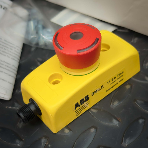 Angled view of the ABB Jokab SMILE Emergency Stop Push Button 2TLA030050R0000 from Obtainium Science and Surplus, showing its yellow housing and red button.