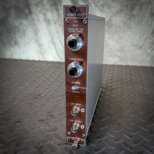 Ortec 550 SCA Single Channel Analyzer NIM BIN Module from Obtainium Science and Surplus, shown standing on a metal surface with labeled front controls and connectors.